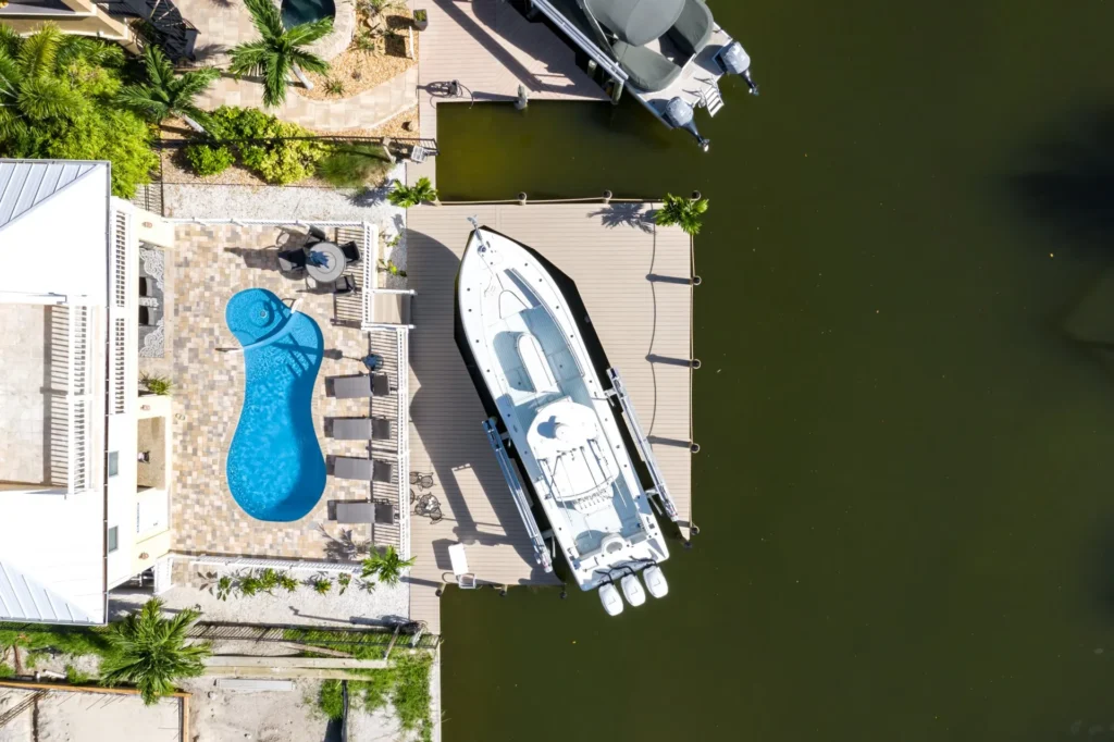 Aerial view of a large boat docked at a spacious waterfront dock surrounded by calm waters.