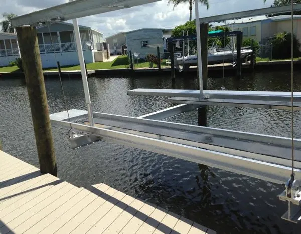 Aluminum boat lift frame with extended support beams installed near a composite dock on a sunny canal.