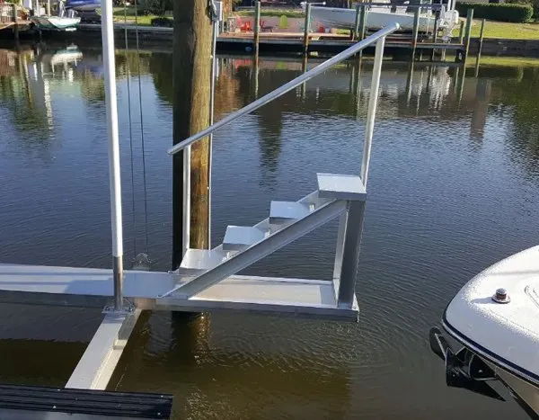 Aluminum dock stairs with railing attached to a boat lift for safe and easy access.