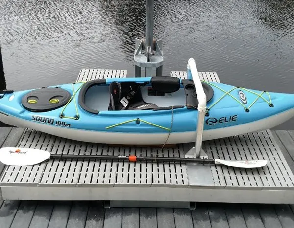 Close-up of a blue kayak secured on a kayak launch platform with a paddle resting below.