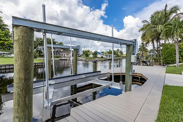 Boat lift frame installed on a canal dock with composite decking and a view of tropical surroundings.