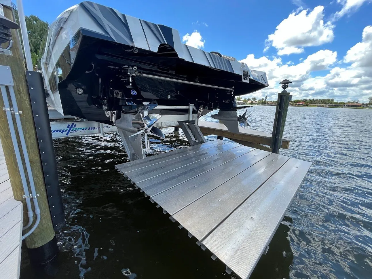 A close-up of a boat lift showcasing the motor and propeller, with a dock and water in the background.