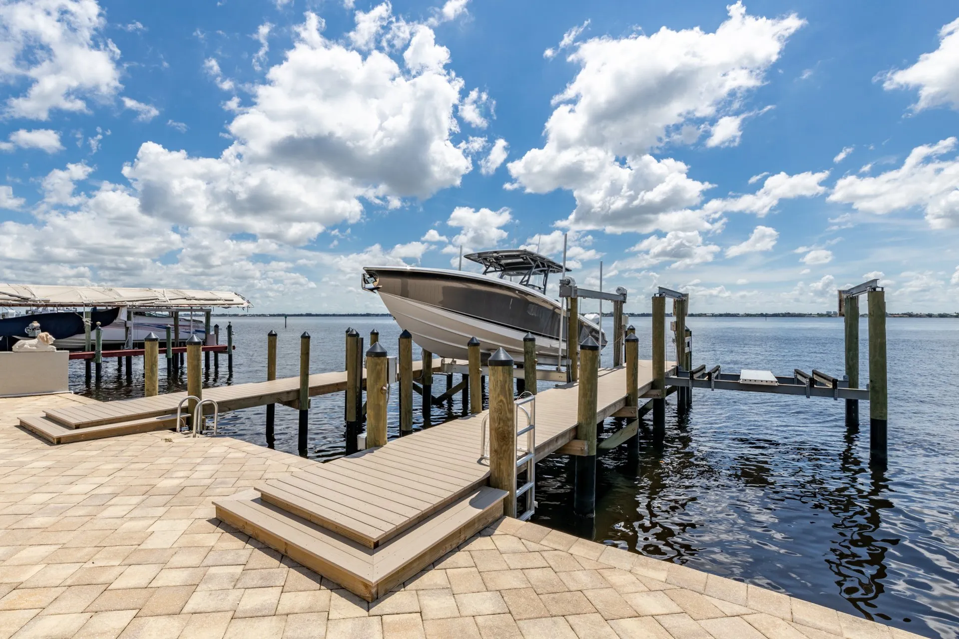 Boat lift dock with waterfront views under a bright blue sky with scattered clouds.