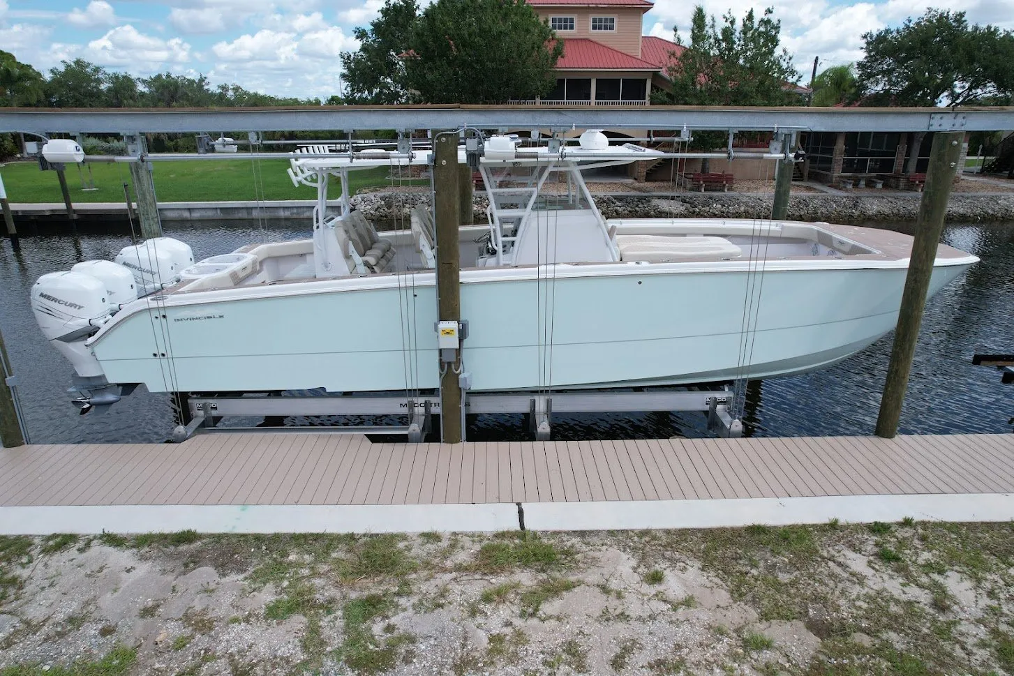 A sleek white boat secured on a lift, shown from the side, with a modern dock and waterfront background.