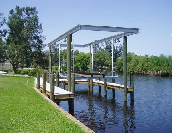 Boat lift frame installed on a canal dock surrounded by lush greenery and calm water.