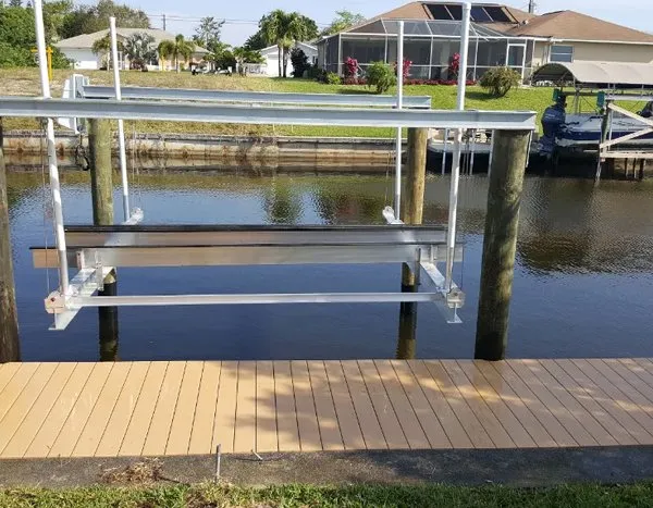 Aluminum boat lift frame installed on a canal dock with wooden decking.