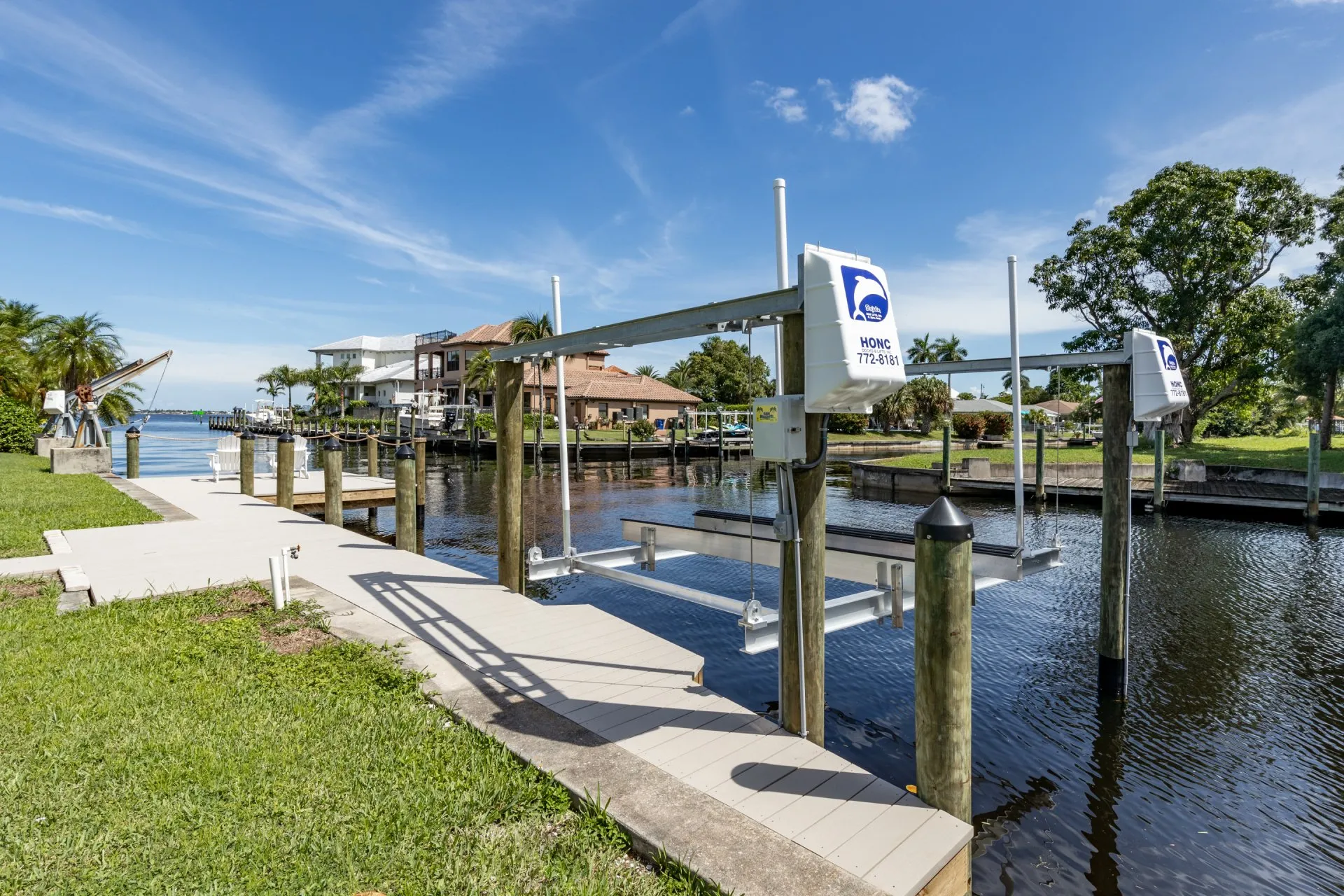 anal-side dock equipped with Honc boat lifts and a view of waterfront properties.