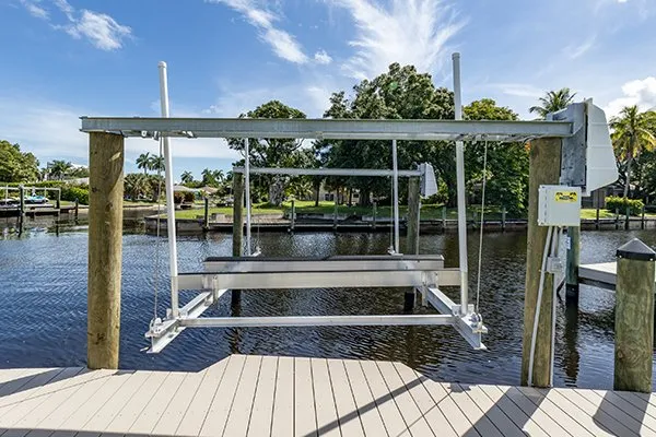 Canal-side boat lift frame installed on composite decking with a scenic waterfront backdrop.