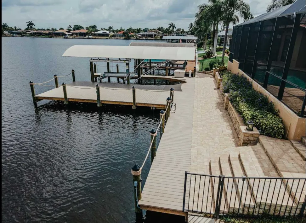 Elegant canal-side dock with a covered boat lift, composite decking, and landscaped patio overlooking the water.