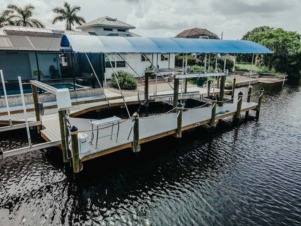 Dock with a covered boat lift system featuring a blue canopy on a calm waterway.