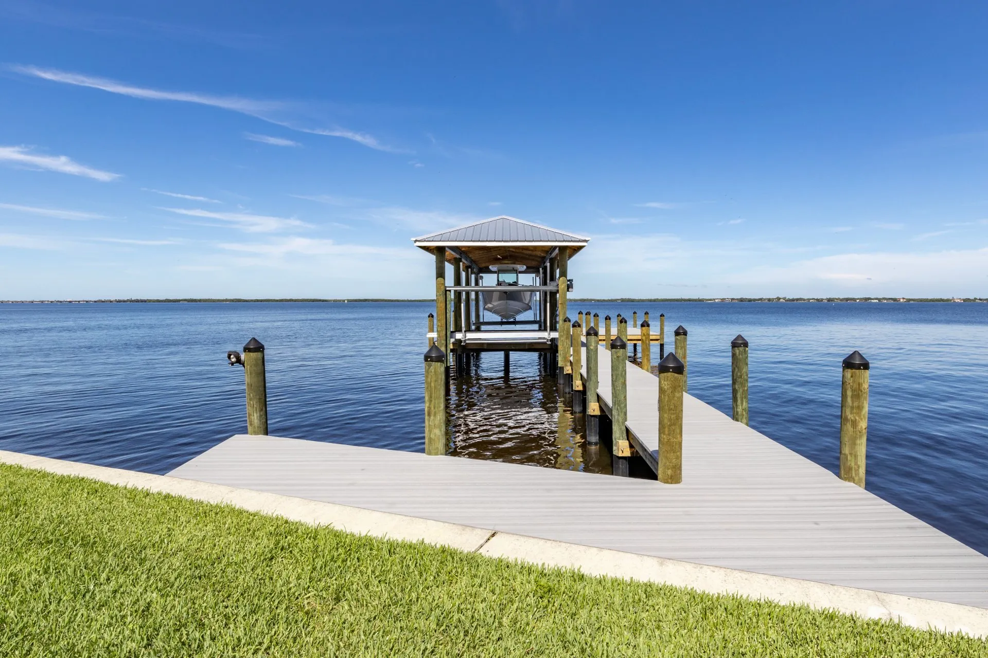 A dock extending into the water with a covered boat lift.