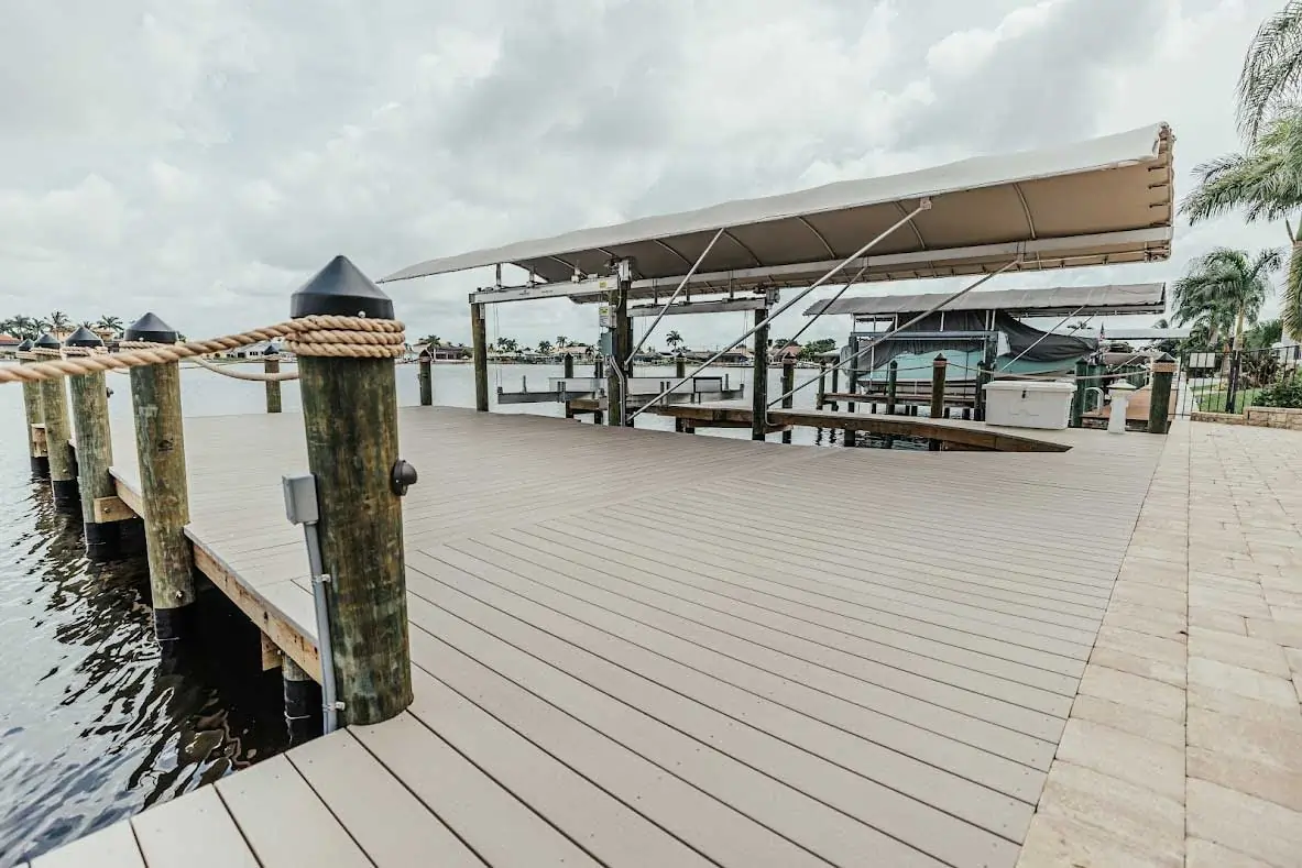 Spacious dock with wooden posts, rope railings, and a covered boat lift on a cloudy day.