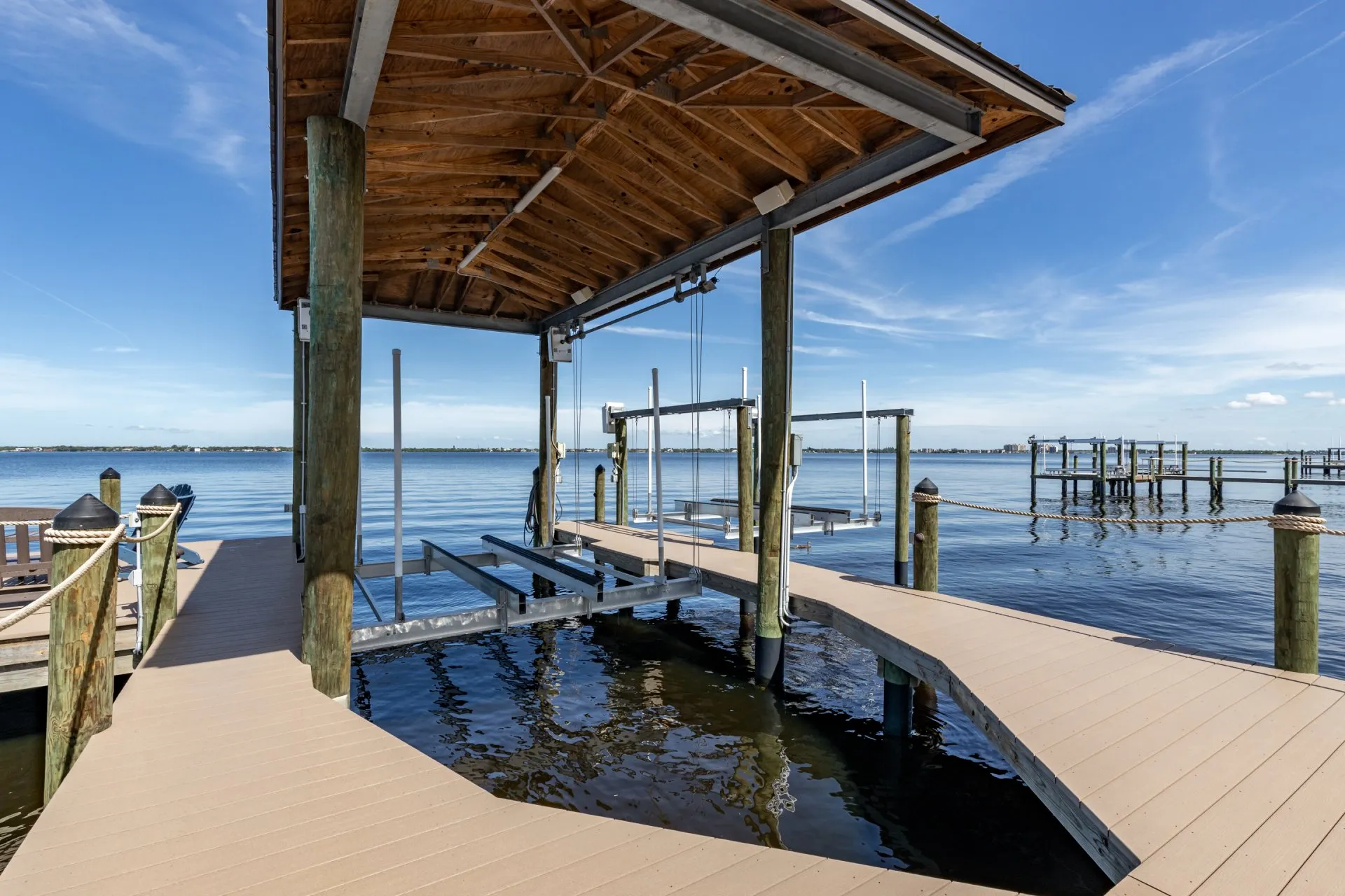 Dock with a wooden pavilion, boat lift structure, and serene water views.