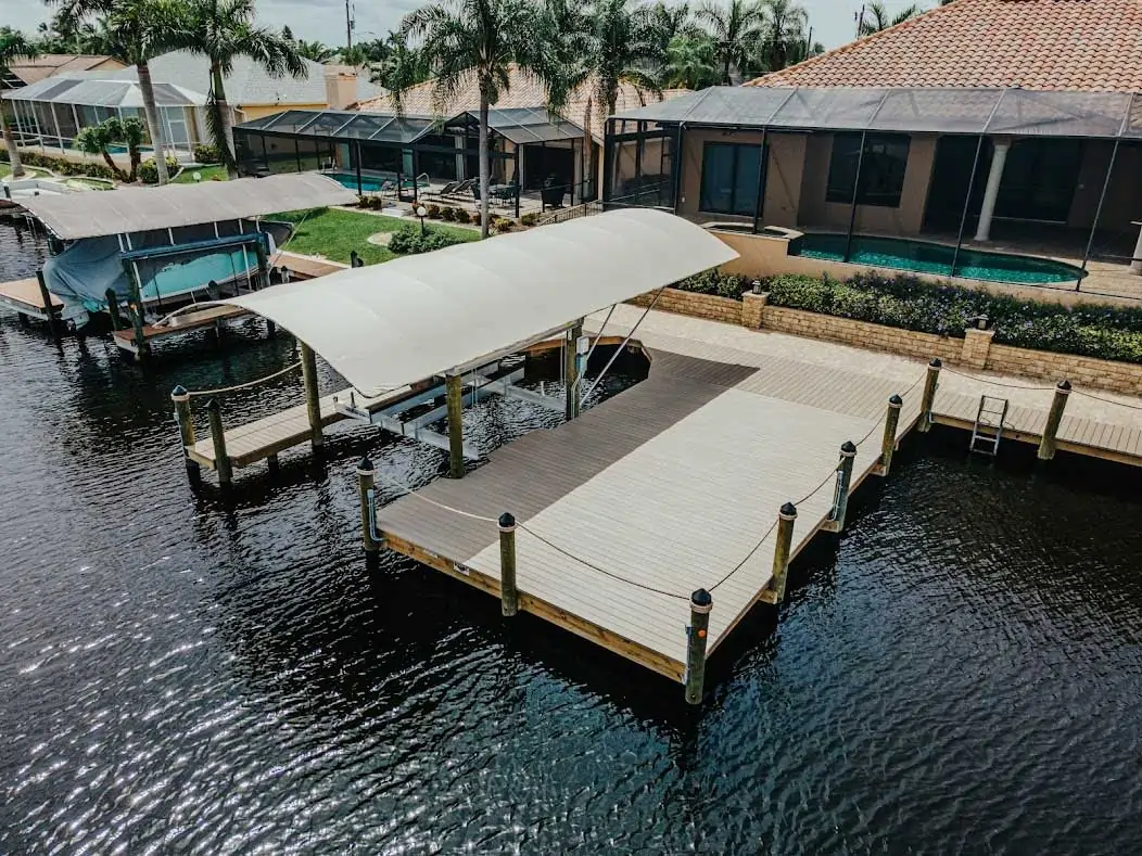 Waterfront dock with a covered boat lift, composite decking, and adjoining poolside area.