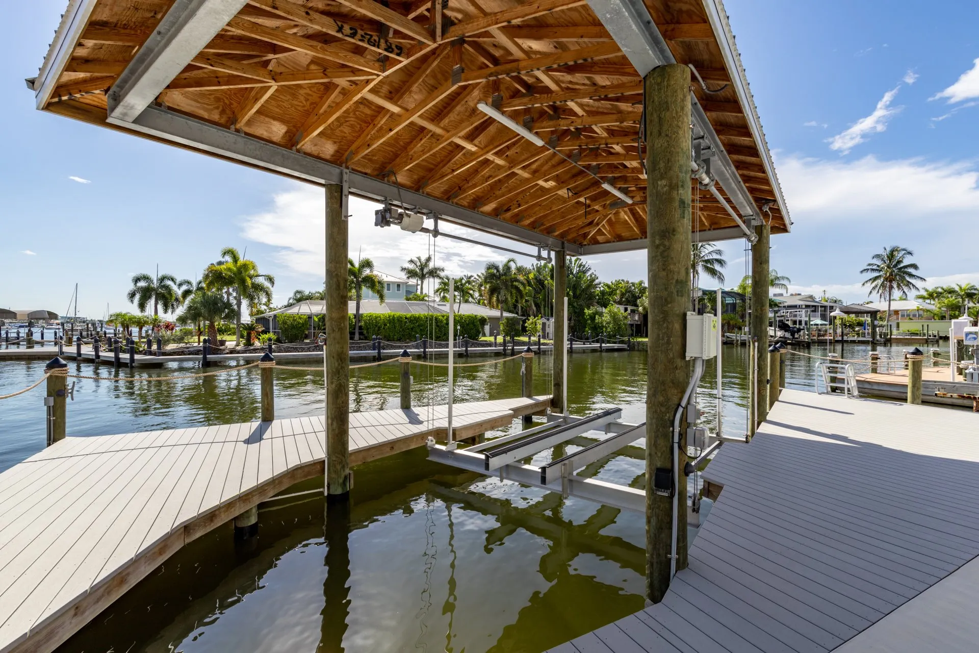 Covered boat lift dock with wooden roofing and modern waterfront design.