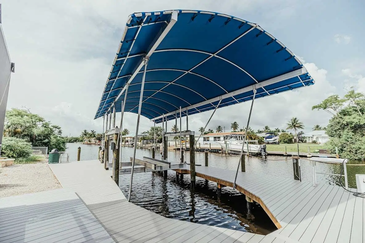 Side view of a dock with a blue canopy and boat lift over a calm waterway.