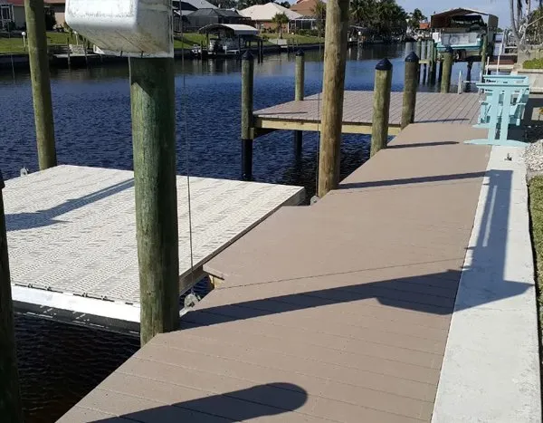 Dock with composite decking, motorized boat lift, and white platform accessory along a calm canal.