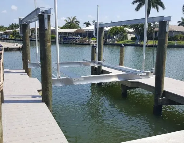 Wooden dock piling with a white cap and a mounted protective bumper along a waterfront.