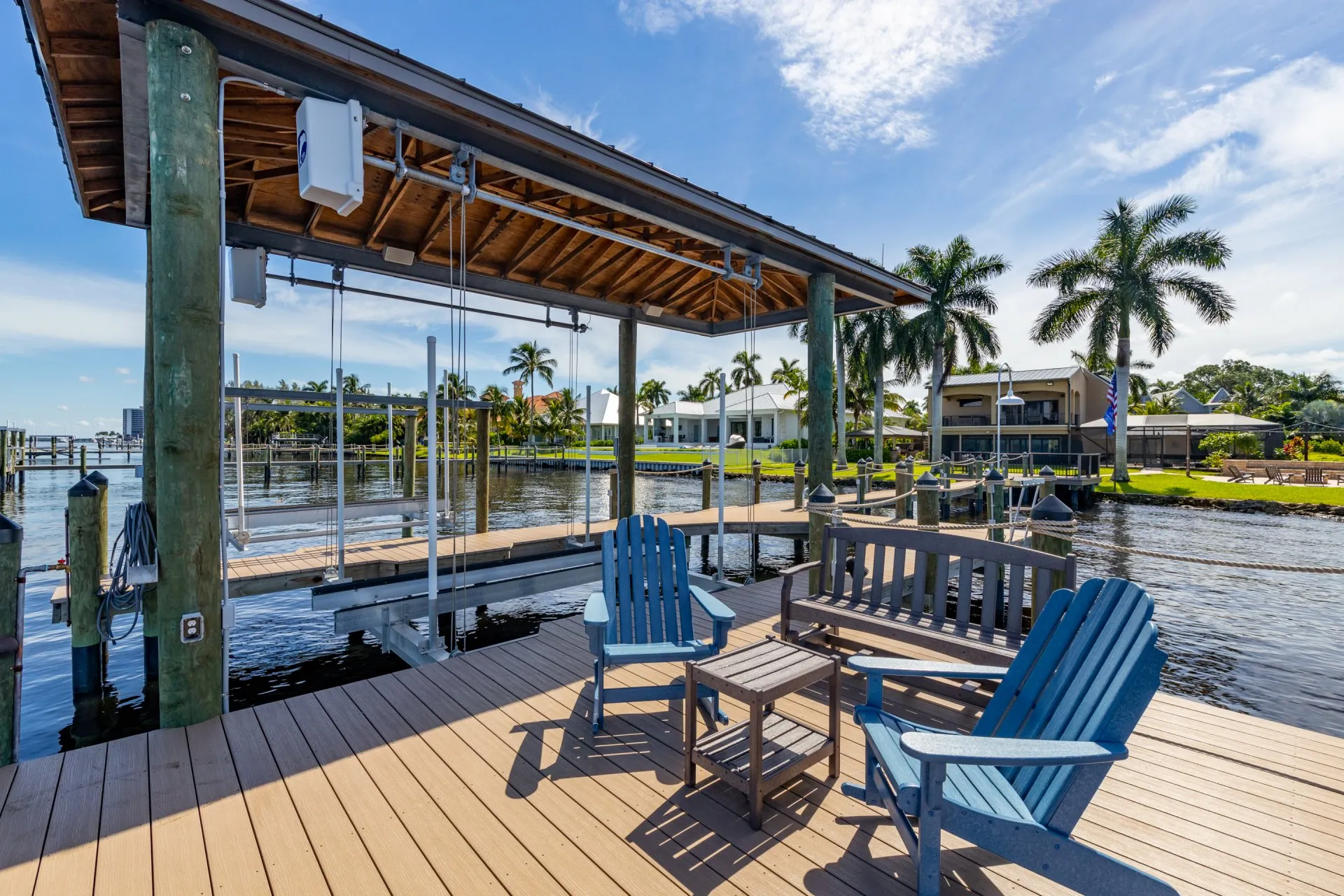 Waterfront dock with a covered pavilion and Adirondack chairs.