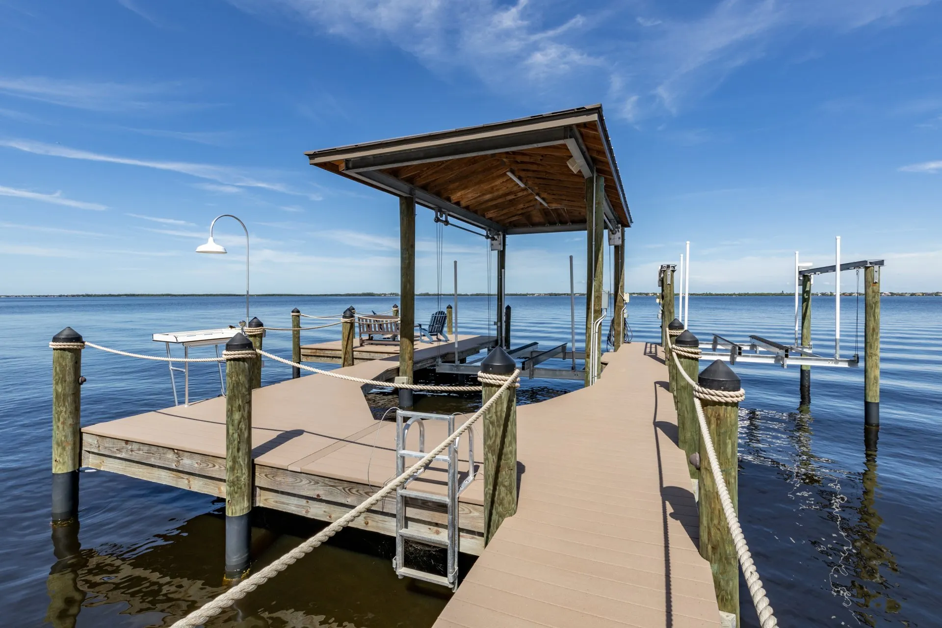 Dock with a covered pavilion, rope railings, and boat lift overlooking calm waters.