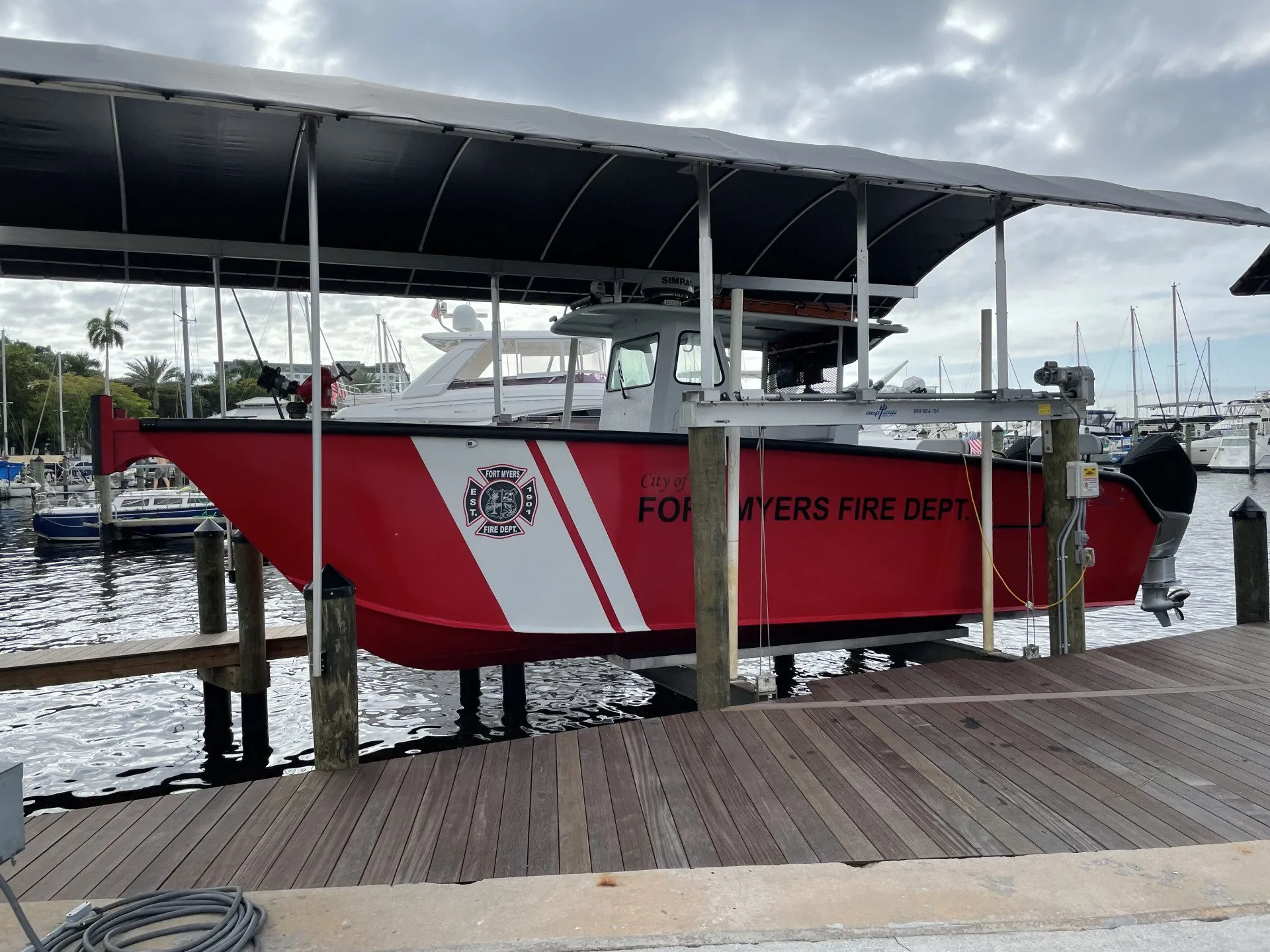 Fort Myers Fire Department rescue boat secured on a custom lift with a covered dock at the marina.