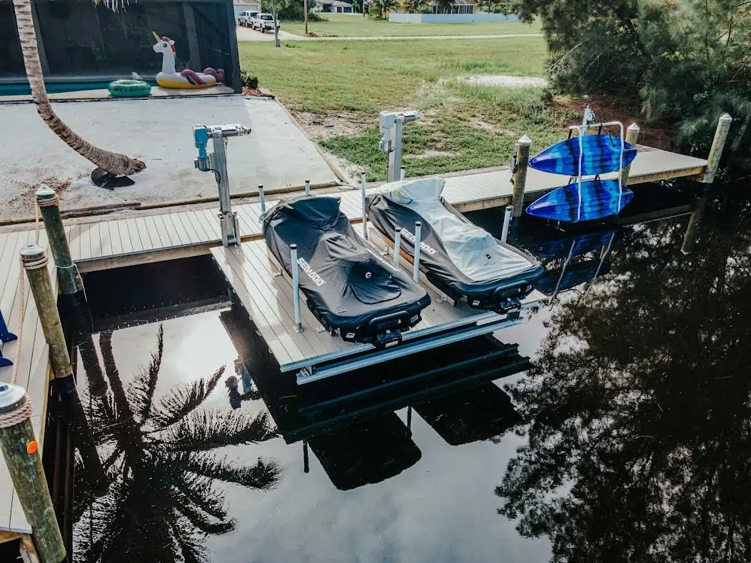 Dock featuring two jet skis on lifts alongside paddleboards and a serene waterfront backdrop.