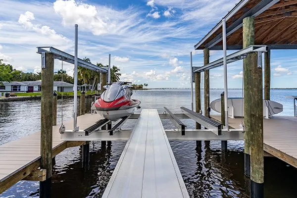 Jet ski parked on a boat lift installed on a canal dock with a covered area and open waterfront view.