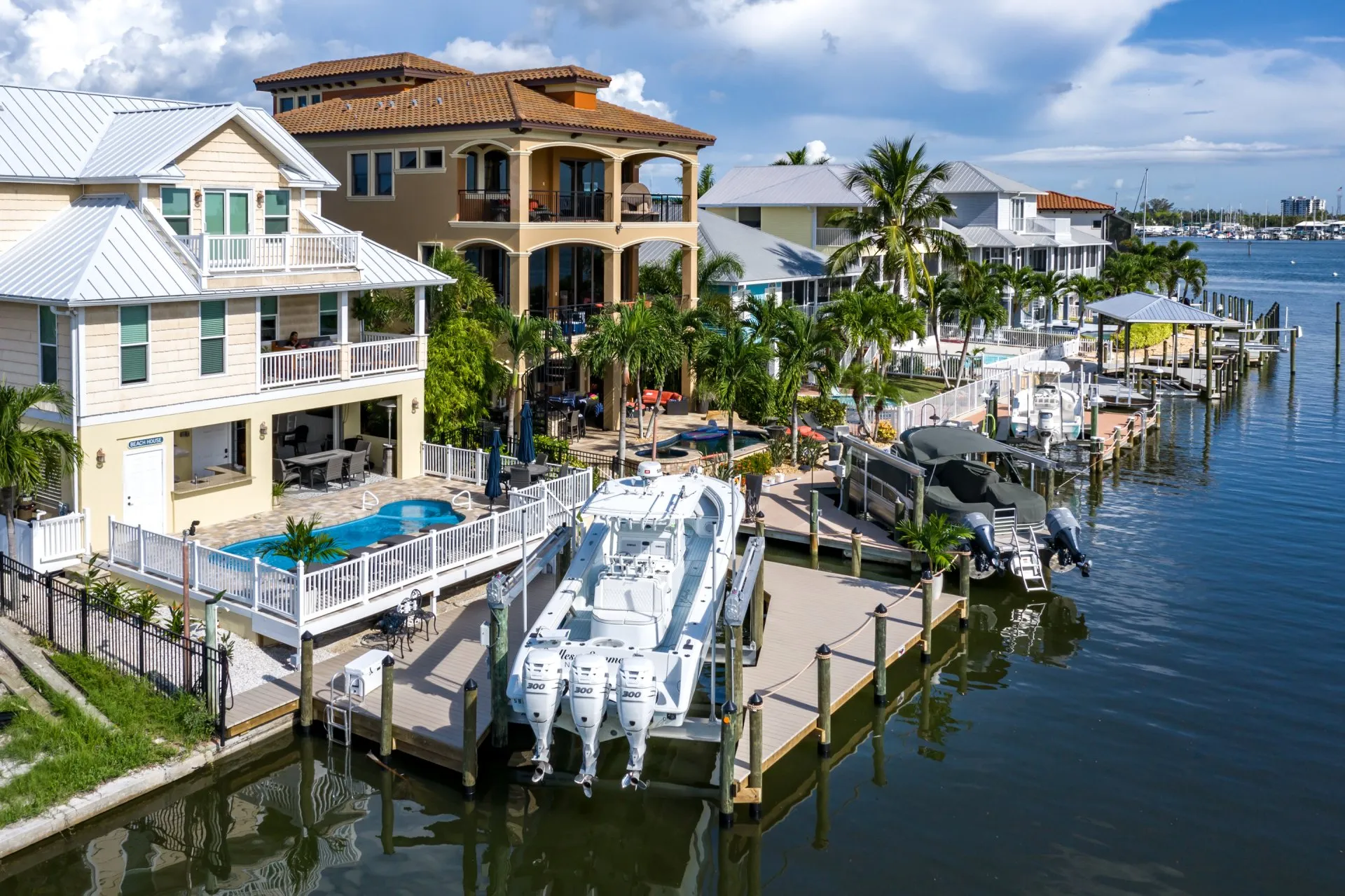 A row of luxury waterfront homes with private docks, featuring a pool and boats.