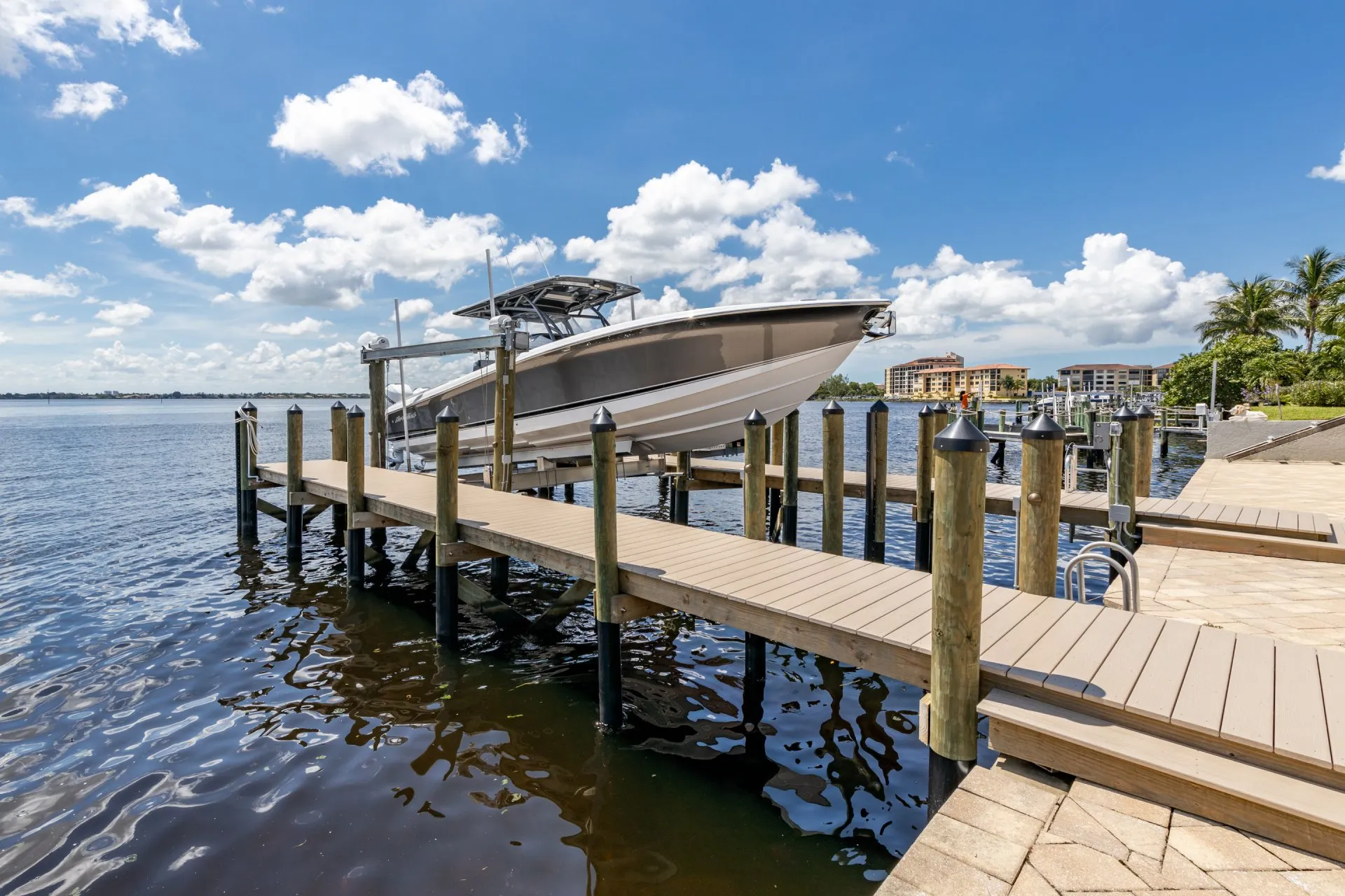 A sleek boat on a modern lift dock with waterfront views under a sunny blue sky.