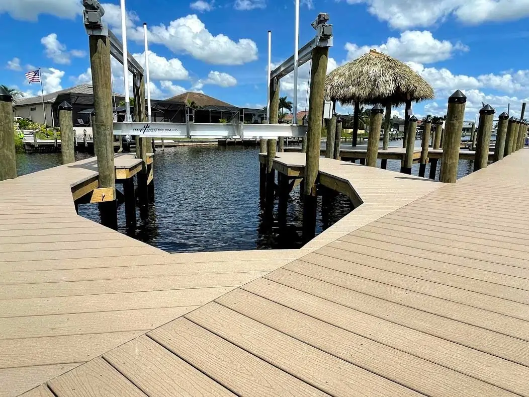 Composite dock with a boat lift and thatched tiki hut on a sunny waterfront.