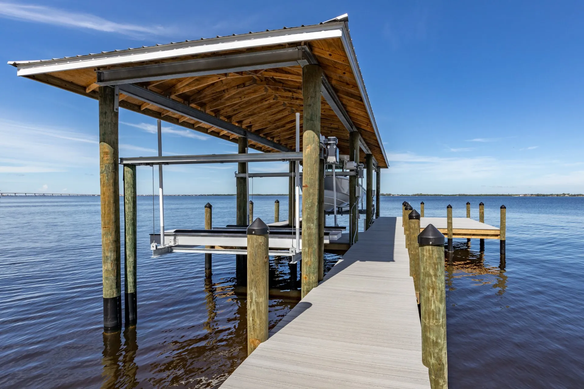 Covered dock with a boat lift extending over calm water.