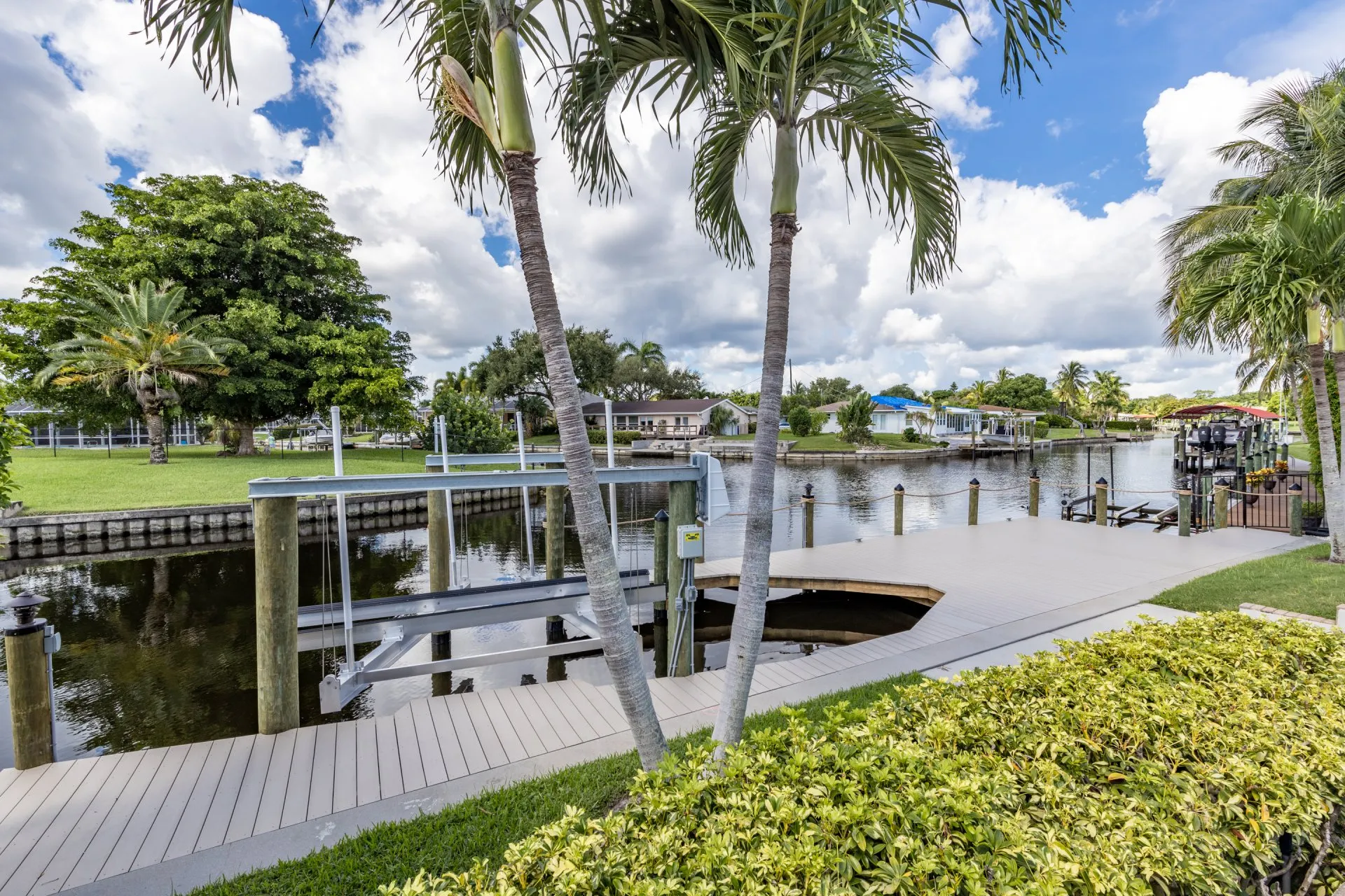 Palm trees framing a dock along a quiet residential canal with lush greenery and vibrant homes.