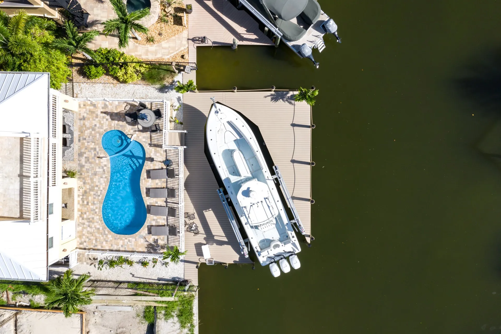 Aerial view of a poolside area and a docked boat at a waterfront property.