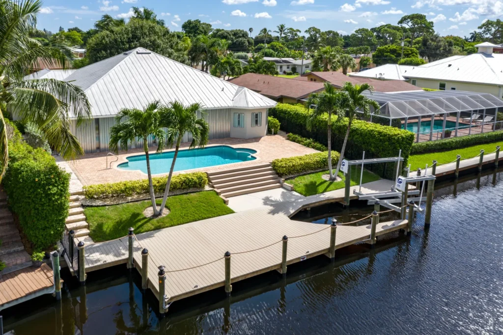 A private dock with a boat lift and steps connecting to a nearby pool deck in a waterfront property.