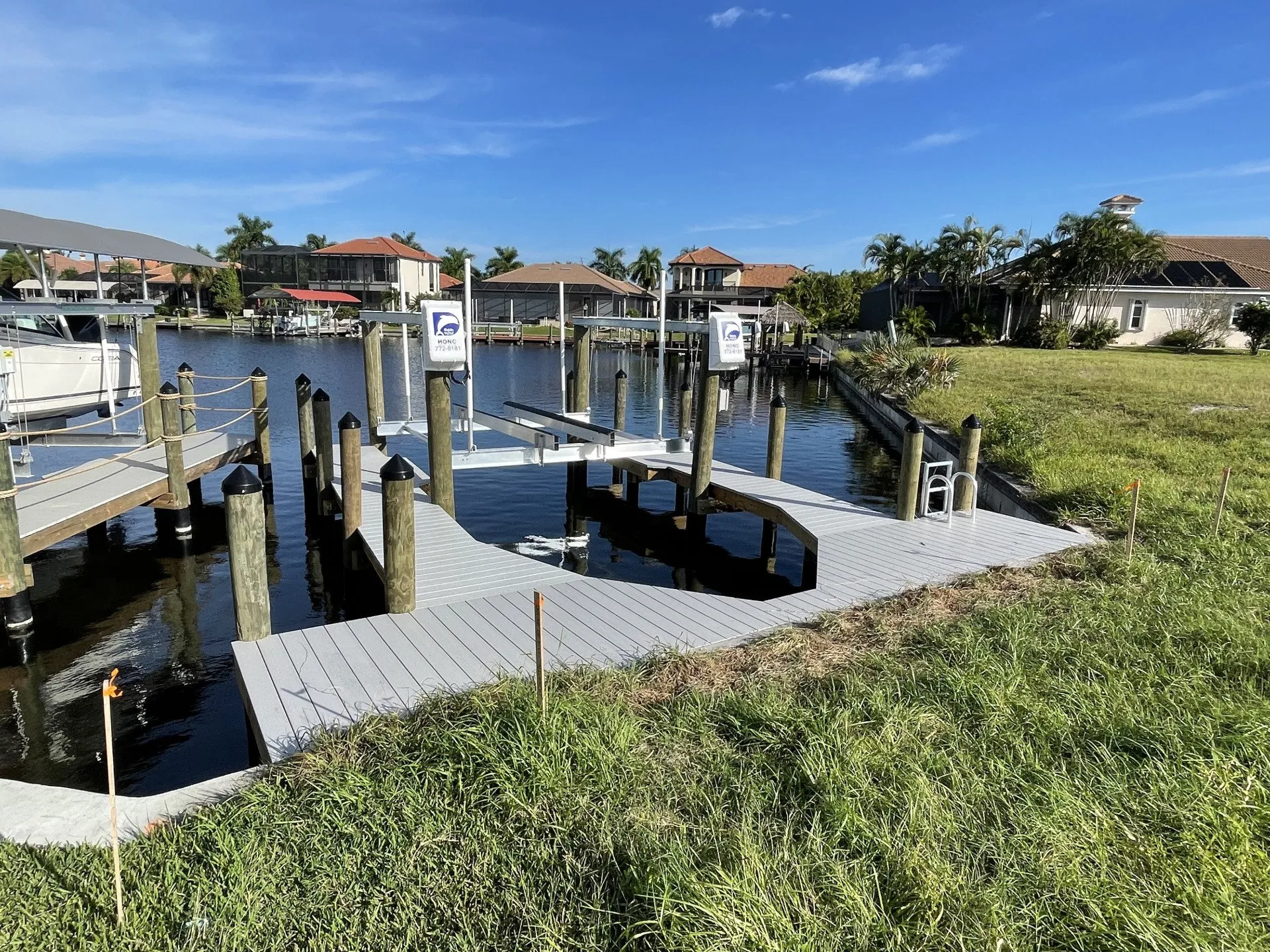 A residential dock with a custom boat lift and spacious walkway along a quiet canal.