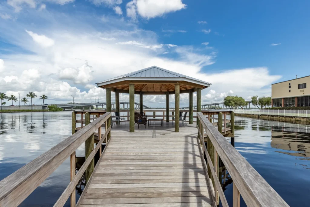 A riverside pavilion dock with a shaded seating area and a sturdy platform overlooking the water.