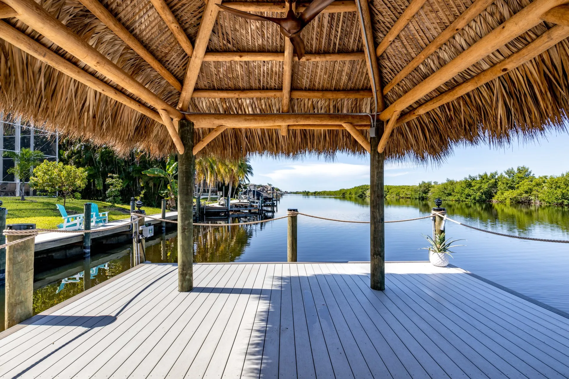 Tiki hut on a dock overlooking calm water with mangroves and vibrant greenery in the background.