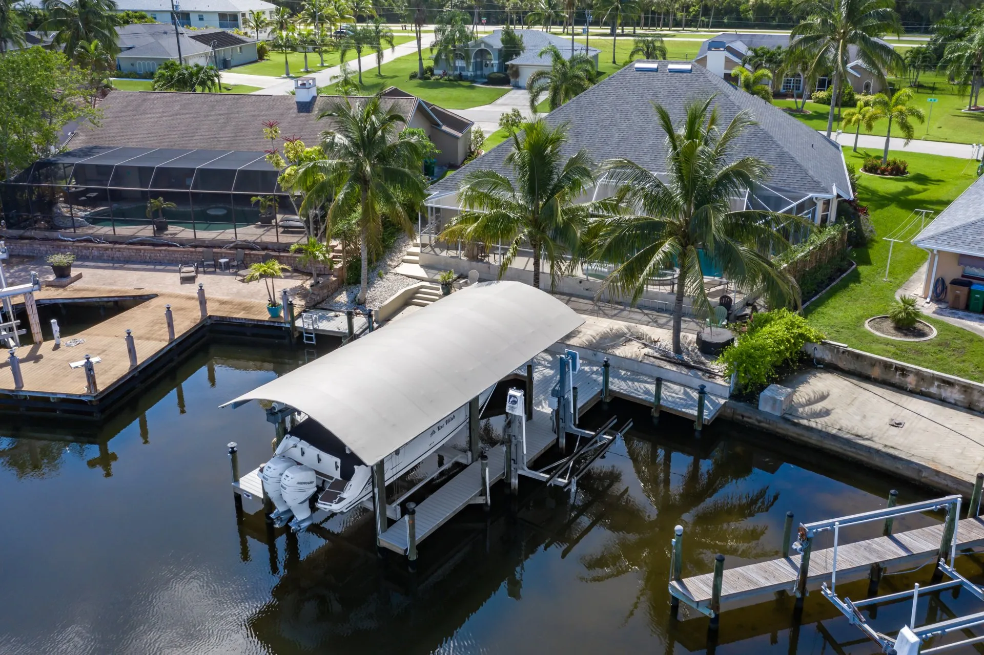 Elevated boat under a canopy on a waterfront dock with lush tropical surroundings.