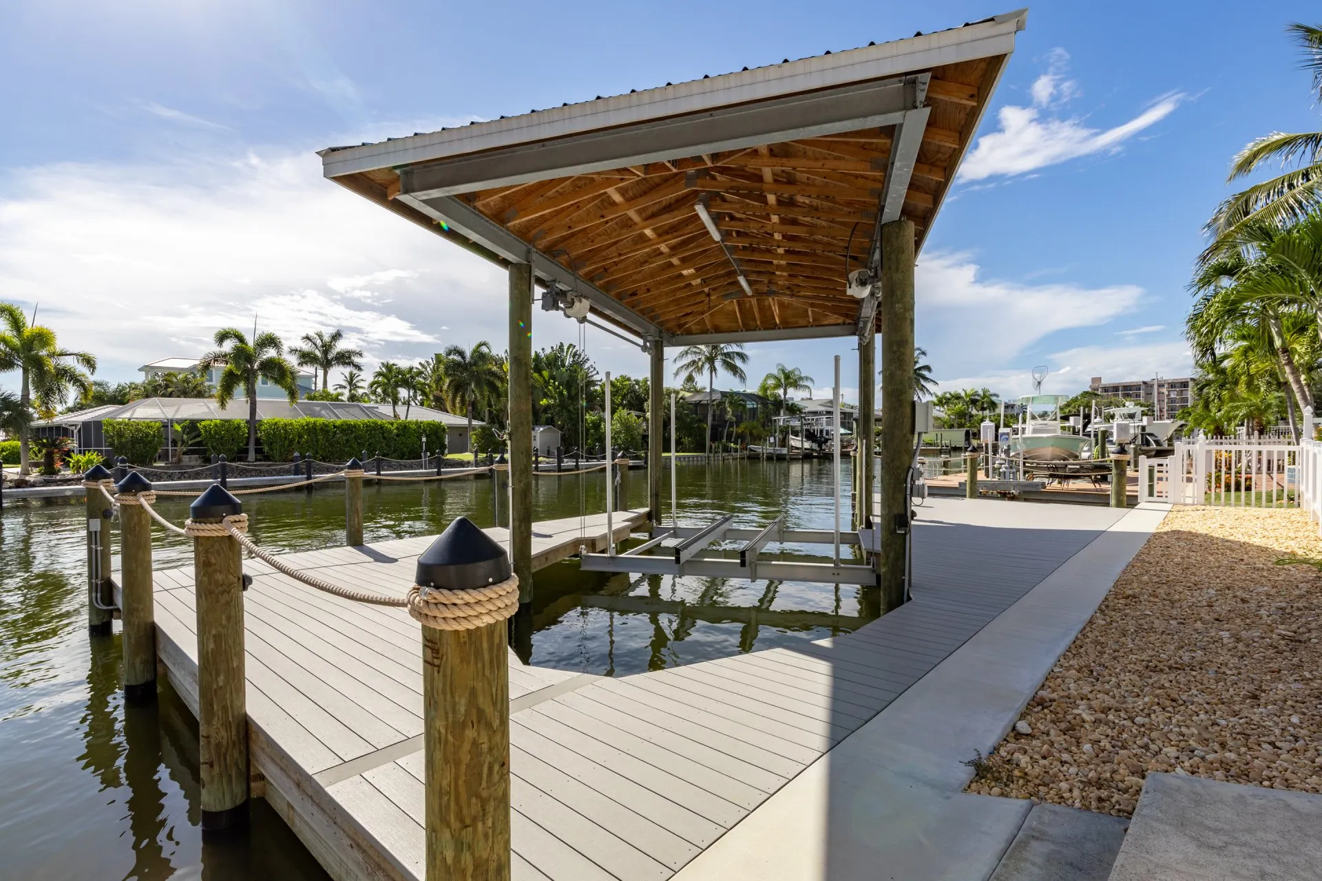 Covered dock with boat lift and rope-secured pilings in a serene waterfront setting.