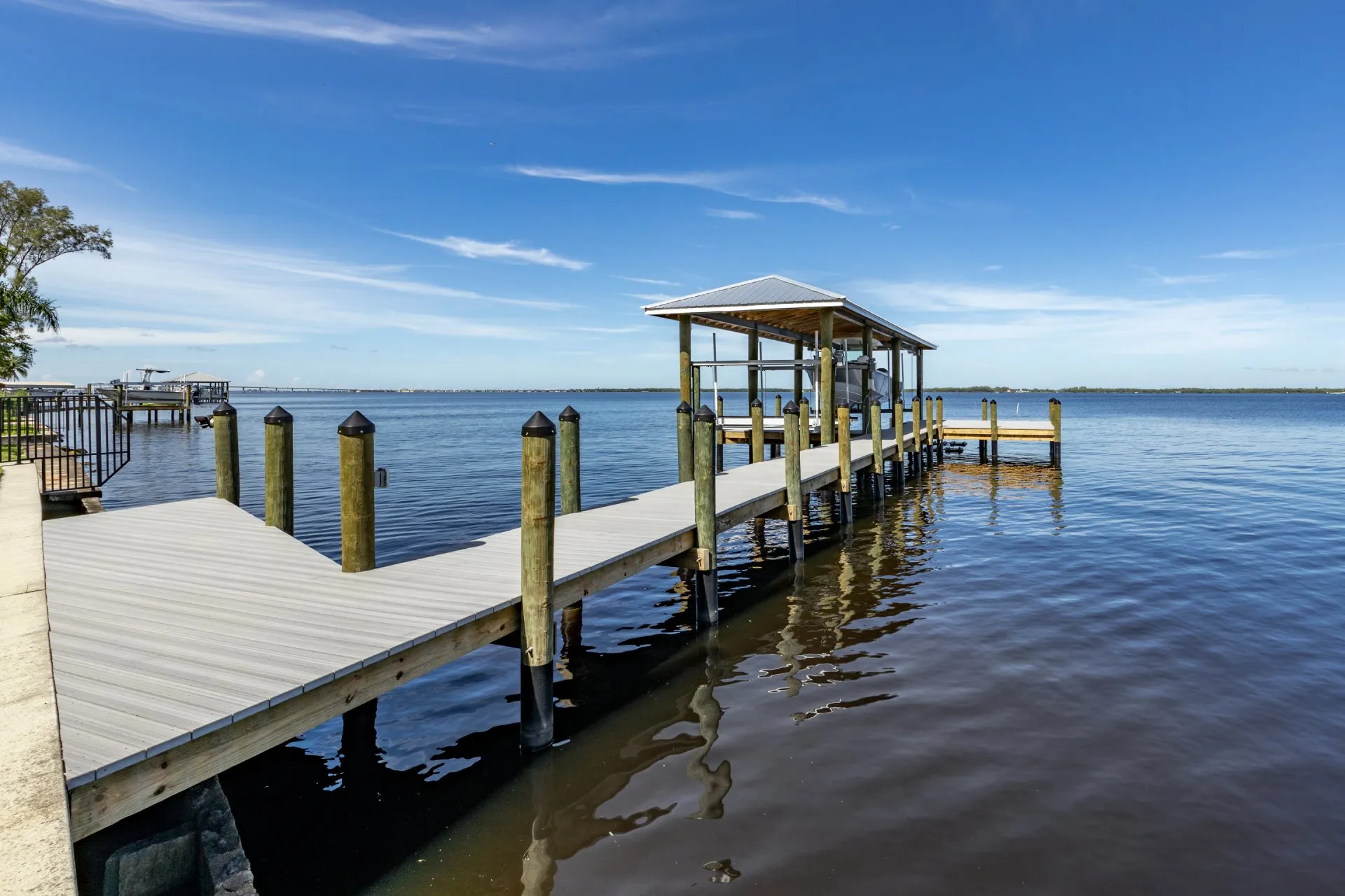 A waterfront dock with a covered boat lift extending over calm waters.