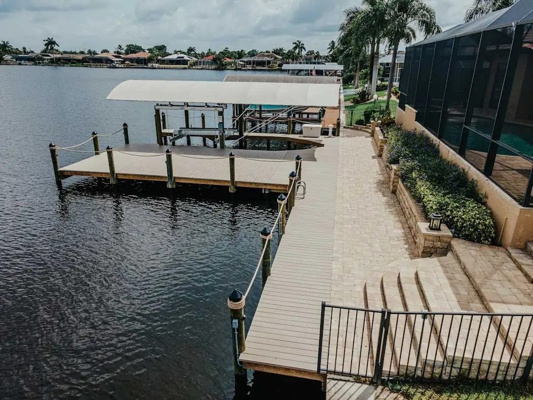 Waterfront dock with a covered boat lift, landscaped walkway, and a view of calm waters.