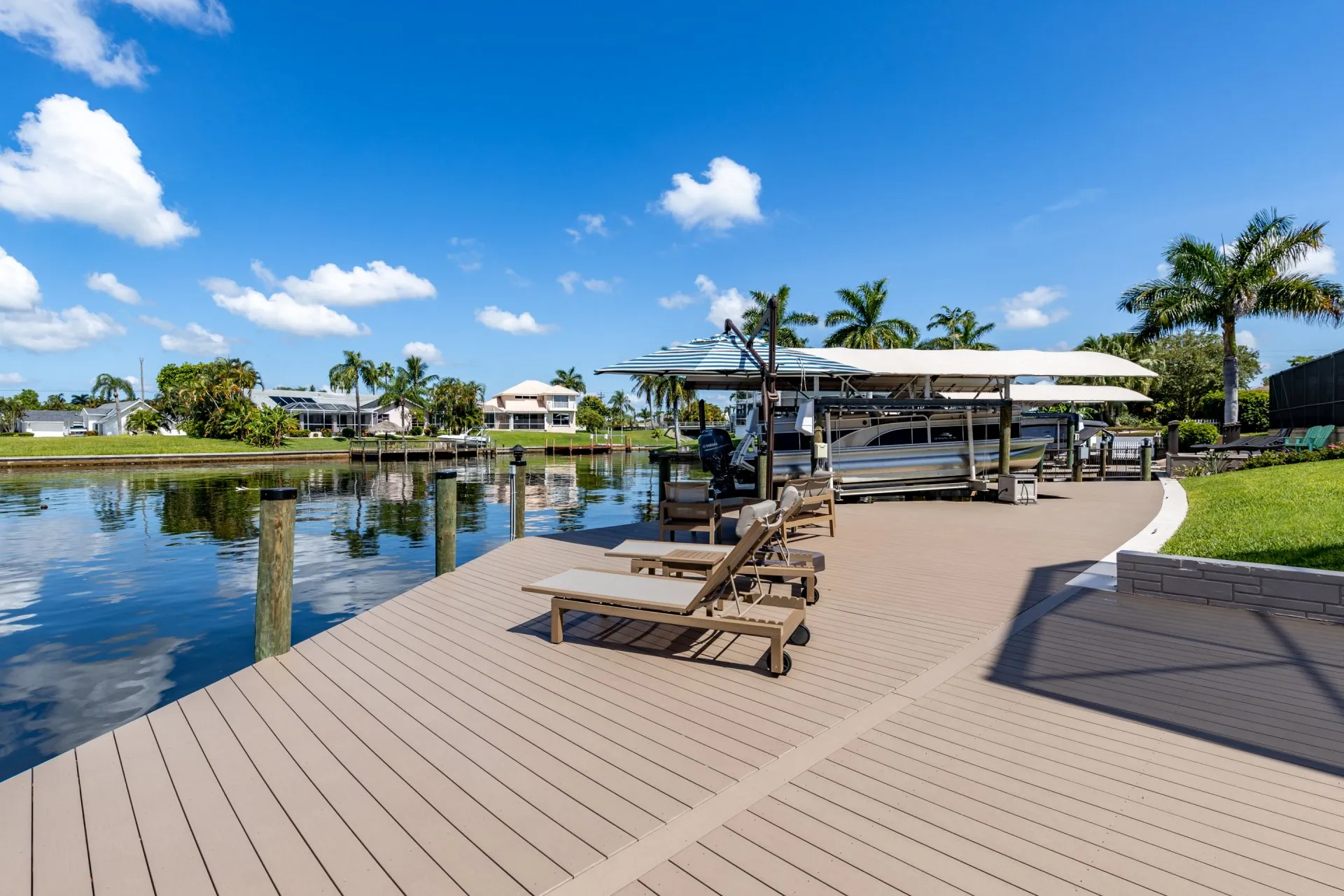 Spacious dock with lounge chairs and a boat lift overlooking a calm waterfront.