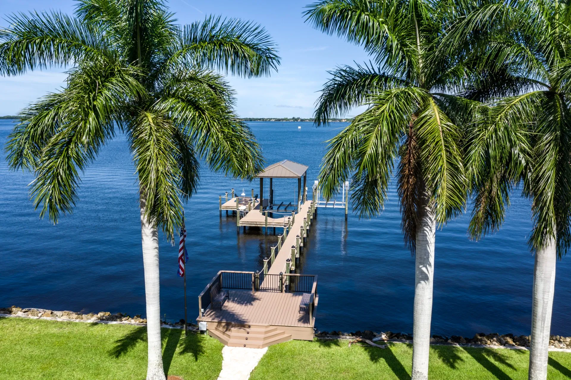 Scenic dock view framed by tall palm trees overlooking calm waterfront.