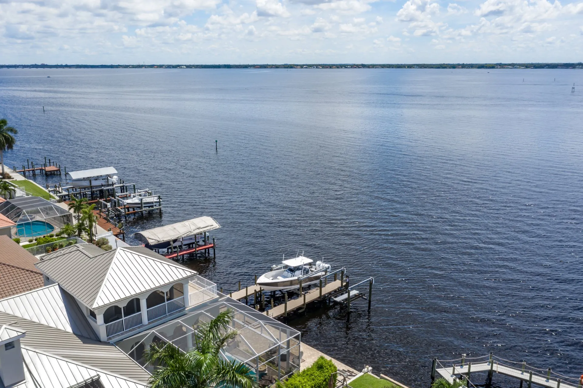 Aerial view of waterfront properties with docks and boat lifts on a calm, expansive body of water.