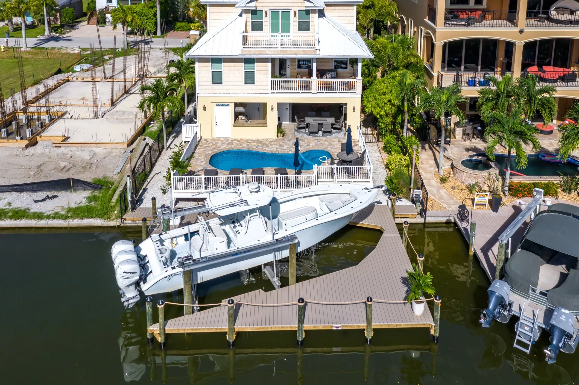 A luxurious waterfront home with a pool and an adjacent boat dock featuring a sleek white boat.