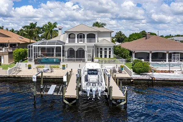 A luxurious waterfront mansion featuring a screened pool, private dock, and boat lift with a large boat.