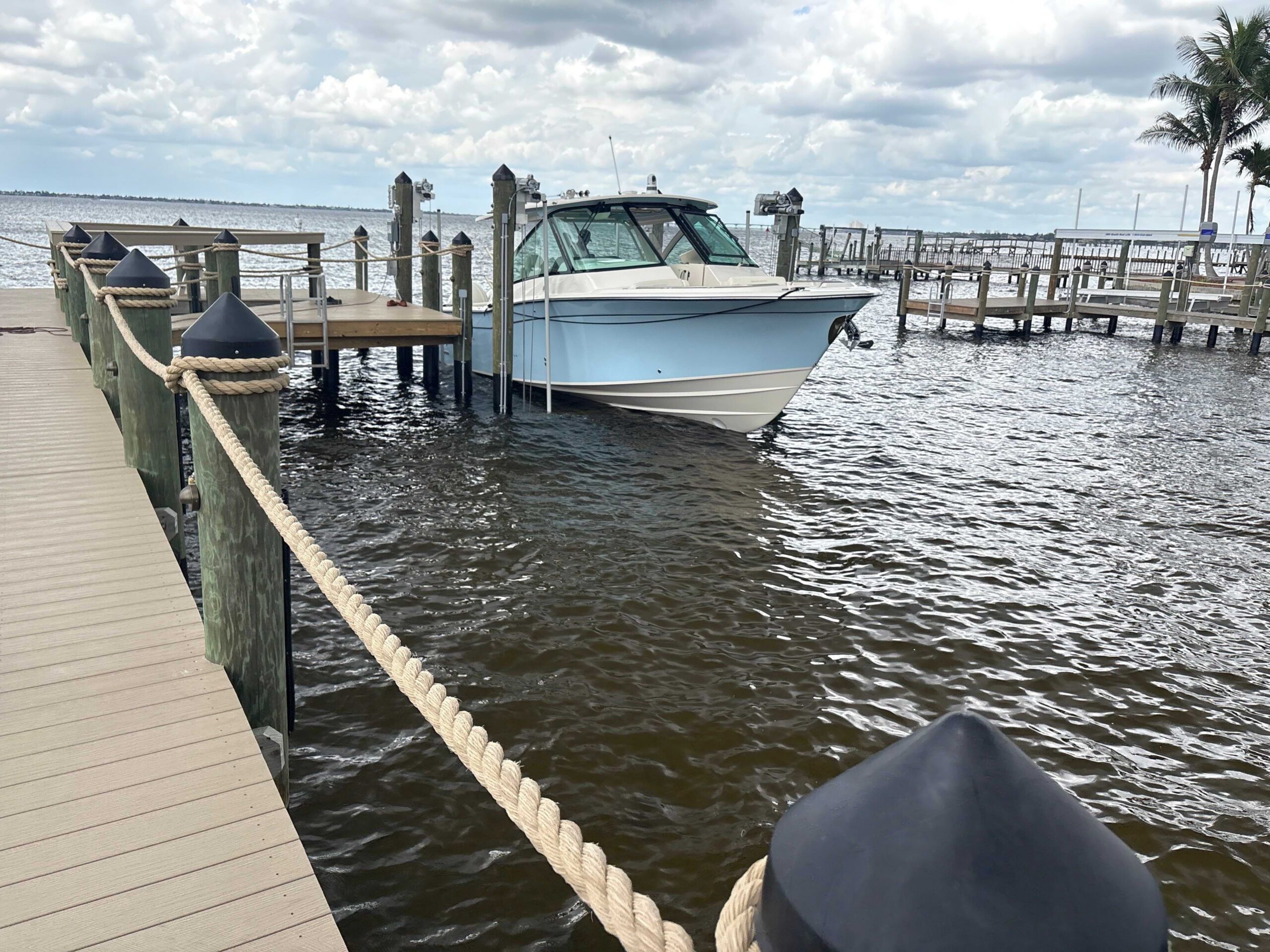 Waterfront dock featuring rope railing and a center console boat secured on a four-post boat lift.